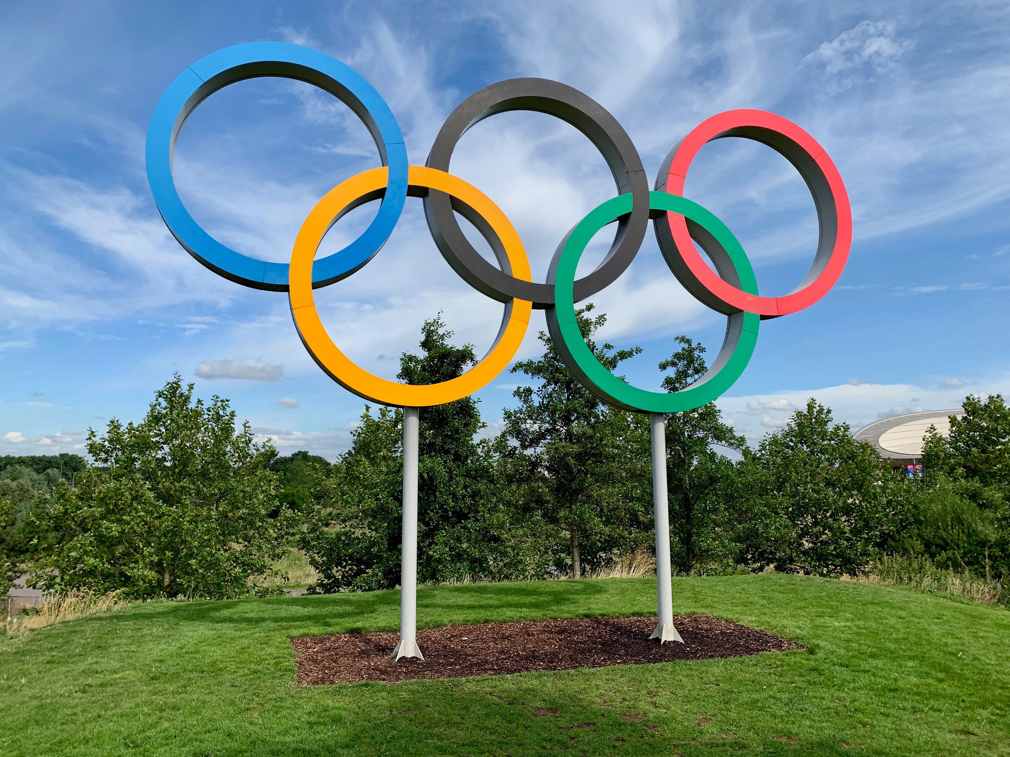 Olympic Rings with blue sky and bushes in the background