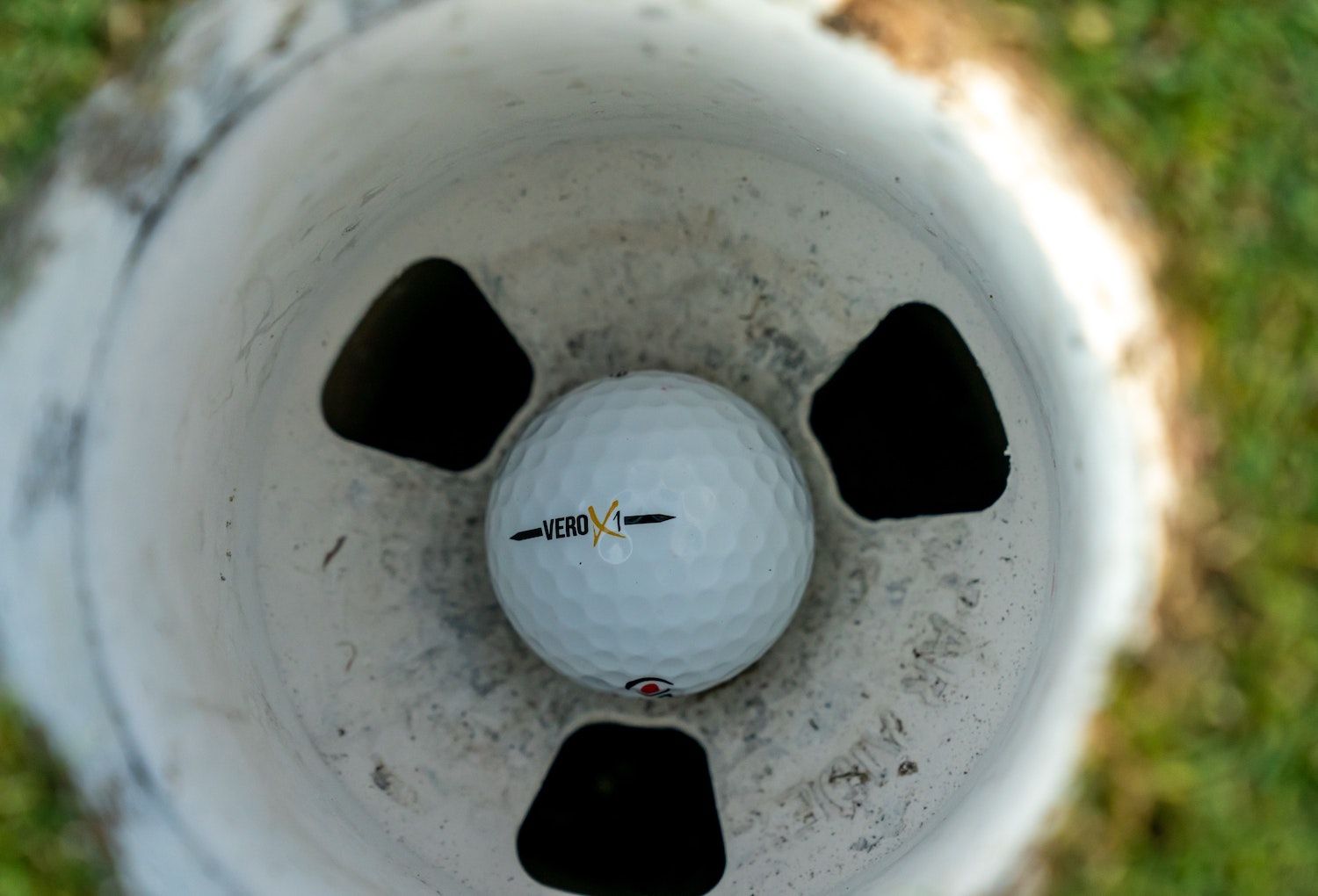 Golf Ball rests in the bottom of a golf hole.