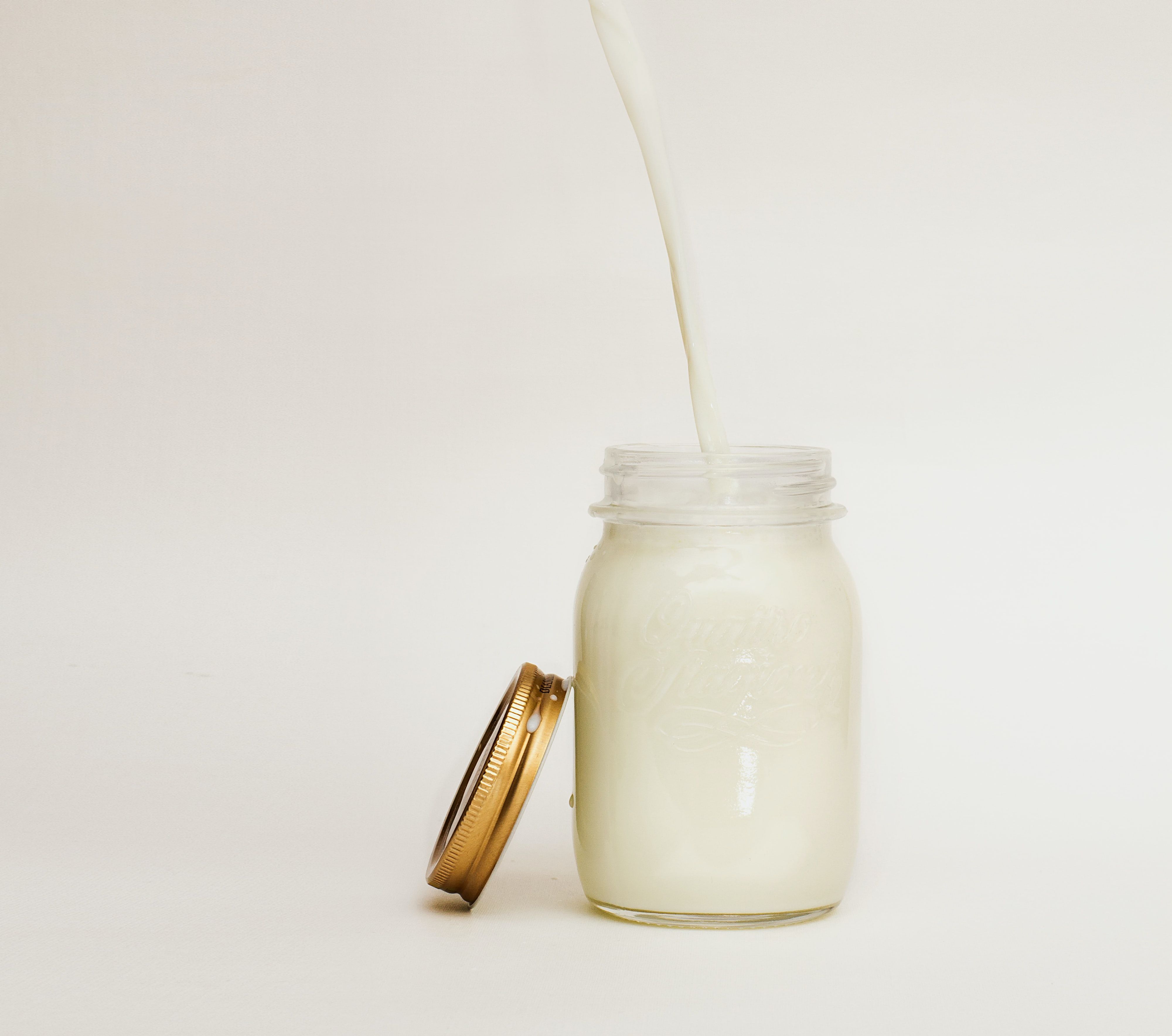 Milk being poured into a jar of milk