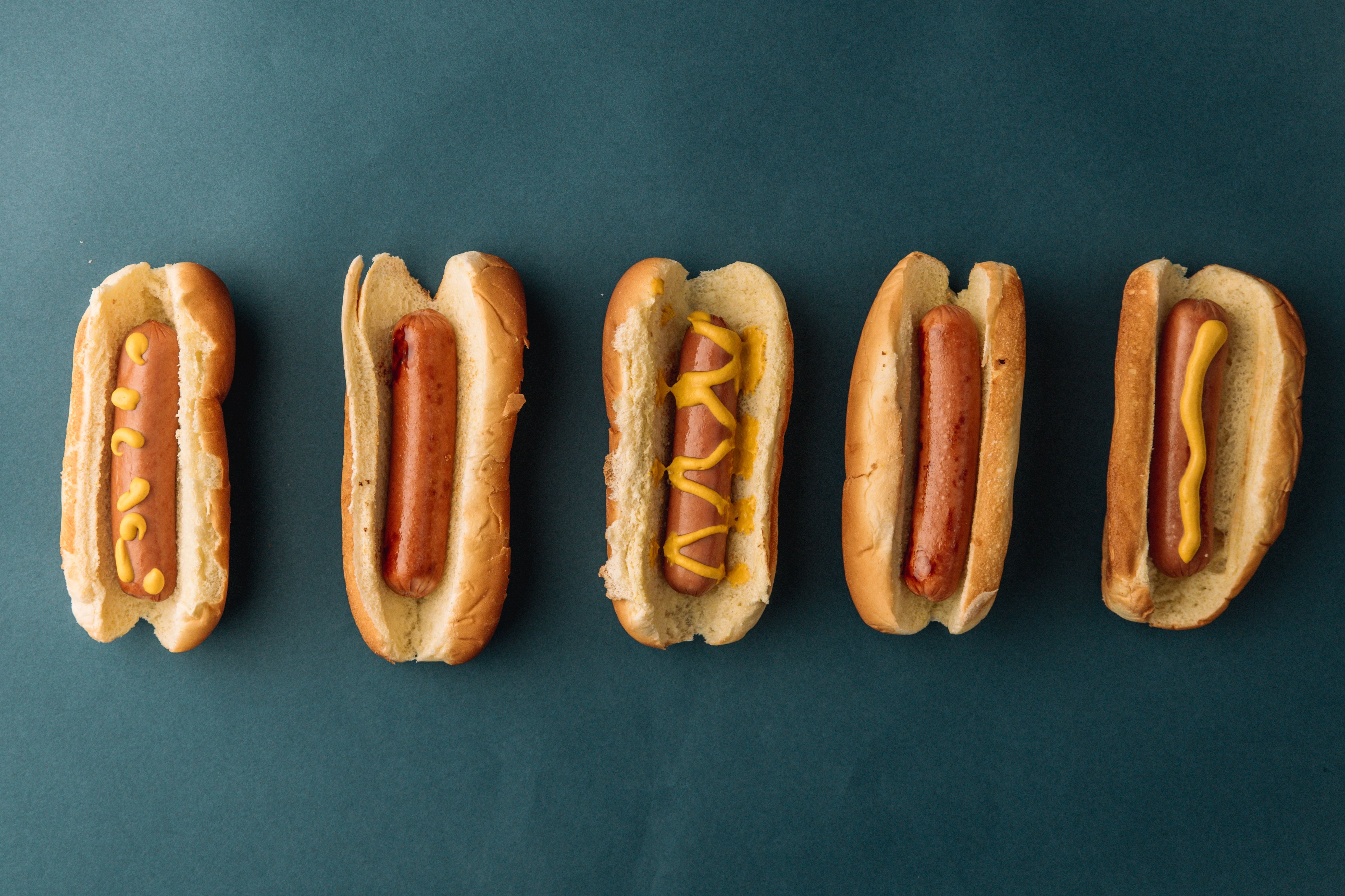 Five hot dogs lined up in a row