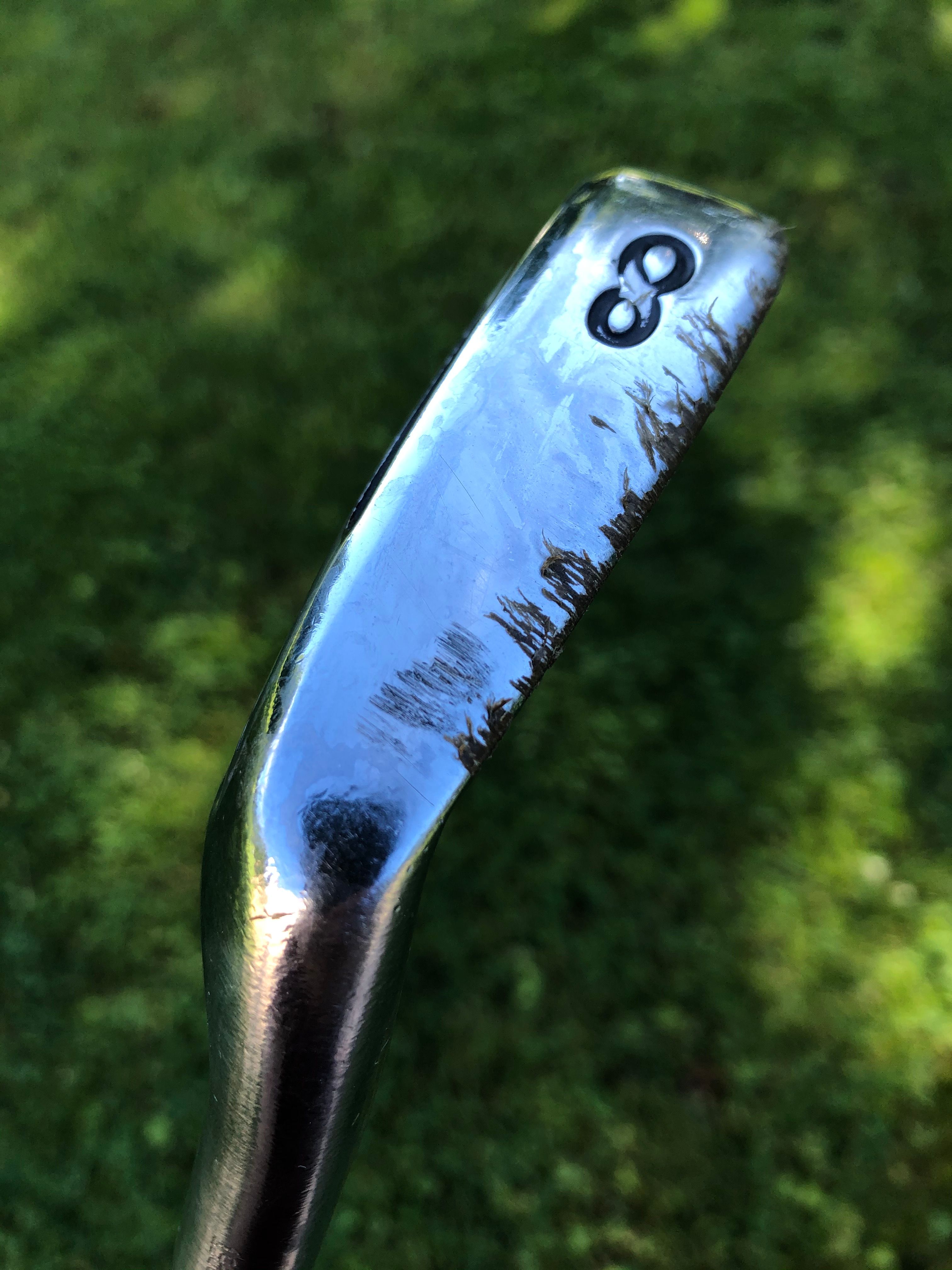 The sole of a golf club stained with turf from artificial hitting mats